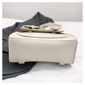 Détail de la base du sac à dos blanc cassé avec pieds en métal et logo de mode latéral