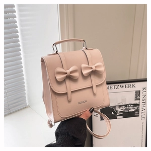 Vue détaillée du mini sac à dos beige avec nœuds papillon et lettrage FASHION