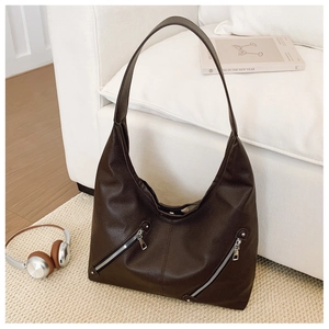Close-up of pebble leather texture and silver diagonal zippers on dark brown hobo tote bag