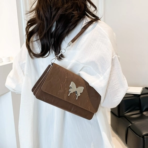 Brown quilted chain bag with silver butterfly charm shown on model in a minimalist setting