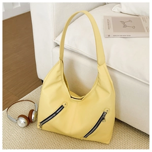 Detail of yellow lychee texture tote bag with metal zippers on beige woven rug