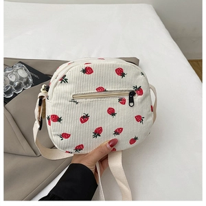 Detail of corduroy mini bag showing strawberry print patterns and metal zipper closure