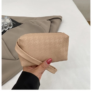Detail of light khaki woven texture clutch bag with chic top handle and minimalist retro style