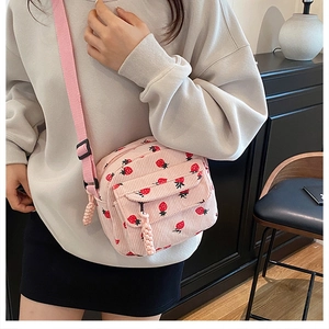 Pink corduroy mini crossbody bag with red strawberry print and adjustable strap detail