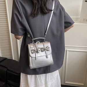 Petit sac à dos argenté avec nœud métallique et pendentif en perles pour femme moderne