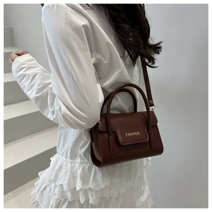 Close-up of brown leather crossbody bag featuring gold 'FASHION' text and handle detail