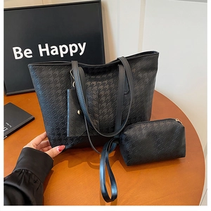 Detail showing black houndstooth embossed tote bag set with matching zipper pouch on wood