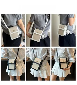 Detail of vertical crossbody phone bag with color-block flap and lace pearl charm