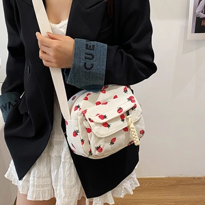White corduroy shoulder bag with red strawberry print and fringe charm detail