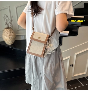 Detail showing retro mini crossbody bag with cream canvas, brown trim and gold floral clasp