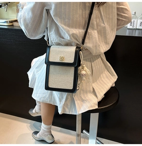 Détail du sac bandoulière en toile avec garnitures trèfles et pendentif poupée en peluche