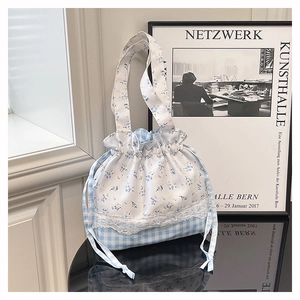 Close-up of floral and plaid bucket bag with white lace trim and drawstring closure