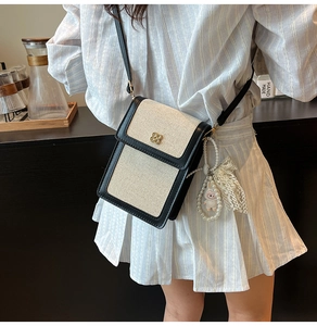 Détails du sac de téléphone croisé avec texture tissée, bordure noire et breloque perle