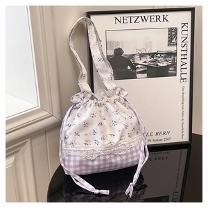 Detail of floral and gingham drawstring handbag with delicate white lace trim insert