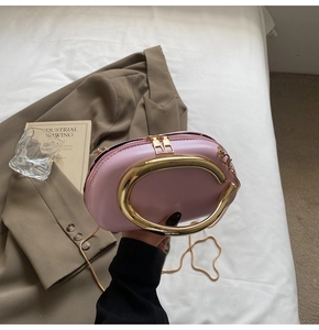 Pink oval evening clutch bag featuring a prominent gold circular metal ring handle