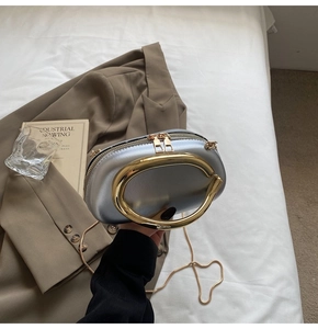 Detail of silver evening clutch with large gold circular handle and fine chain strap