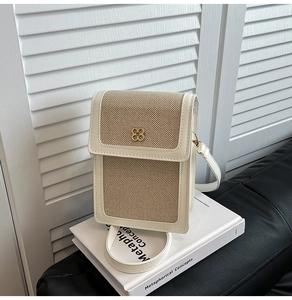Détail du sac de téléphone à bandoulière avec panneau tissé et logo floral doré chic