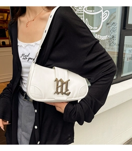 Detailed shot of white leather shoulder bag featuring a vintage gold gothic buckle