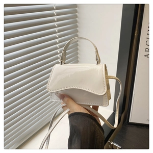Detailansicht der weißen Mini-Handtasche aus glänzendem Lackleder mit eleganter Klappe