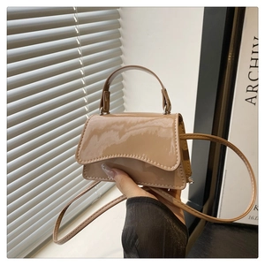 Detail einer Mini-Handtasche aus khakifarbenem Lackleder mit gewellter Klappe und Riemen