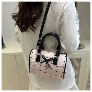 Détail du sac Boston en jacquard rose avec broderies de nœuds noirs et pendentif en cœur