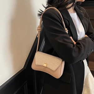 Sac baguette beige chic avec rabat pailleté et bandoulière nouée sur modèle
