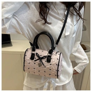 Détail du sac Boston rose avec imprimés nœuds noirs et un pendentif en forme de cœur