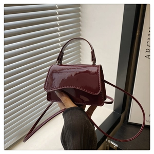 Nahaufnahme der weinroten Lackleder-Minibag mit glänzendem Finish und Handgriff