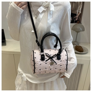 Détail du sac Boston rose avec imprimés nœuds noirs et breloque en forme de cœur
