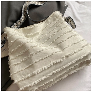 Detailed close-up of cream fringe tote bag with blue patterned scarf strap decoration