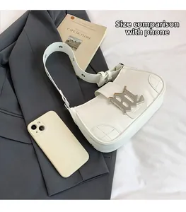 Close-up of white PU baguette bag with silver logo, quilted detail and phone for size reference