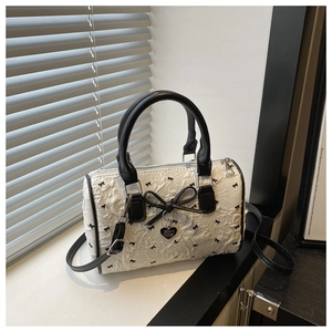 Détail de la texture plissée, nœuds noirs et pendentif cœur du sac Boston