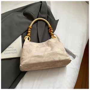 Dettaglio borsa a secchiello in tela floreale con manici in legno e nappa grigia elegante