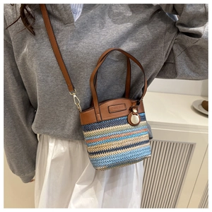 Details der bunt gestreiften geflochtenen Eimertasche mit braunem Ledergriff und Gurt