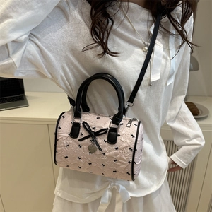 Sac Boston matelassé rose avec nœuds noirs et breloque cœur porté par mannequin