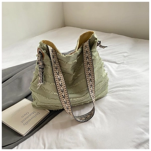 Detail of light green canvas tote bag featuring frayed layers and geometric strap