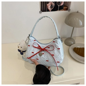 Détail du sac croissant bleu clair avec nœud rouge et pendentif ours en peluche