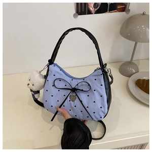 Détail du sac sous le bras à rayures bleues avec motifs cœurs et pendentif en métal