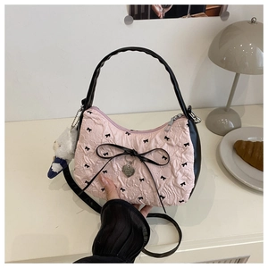 Détail du sac croissant rose avec plis, nœud noir et pendentif en forme de cœur en métal
