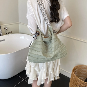 Green canvas tote bag with fringe tassels and patterned woven shoulder strap