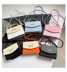 Detail of elegant crossbody bags showing V-quilted faux leather and golden bow accents
