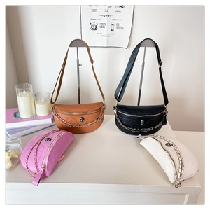 Detail view of embossed leather waist bags with skull metal hardware and chain straps
