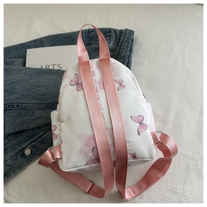 Detail of floral butterfly print on a white canvas backpack with pink adjustable straps