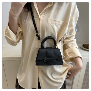 Close-up of black litchi grain leather crossbody bag with curved handle and metal buckle