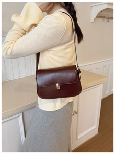 Detail view of deep brown vintage baguette bag with silver metallic clasp on model