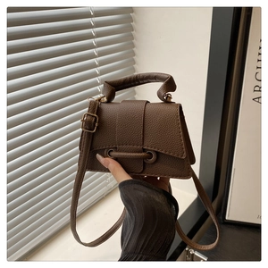 Detail of dark brown litchi pattern leather cross-body bag with gold metal clasp