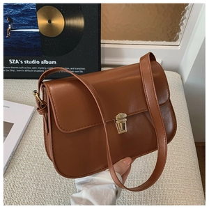 Close-up of vintage brown leather baguette bag with gold metal buckle and flap closure