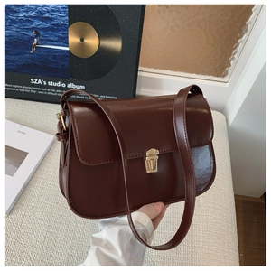Detail of vintage dark brown faux leather baguette bag with golden buckle on a white surface