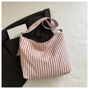 Detail view of red and white striped canvas tote bag texture on a black blazer fabric