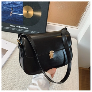 Detail of vintage black leather shoulder bag with elegant gold metal flip lock closure